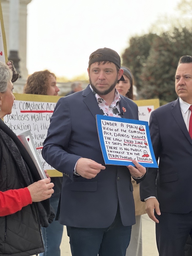 Mark Lee Dickson holds a sign about the Comstock Act in front of the U.S. Supreme Court on March 26, 2024, while justices heard oral arguments in a since-rejected challenge to the abortion pill mifepristone. (Sofia Resnick/States Newsroom)
