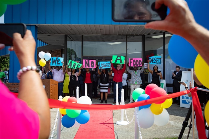 Board members and other stakeholders raise signs reading, “We are no longer a food desert,” at the grand opening of Rise Community Market in Cairo, Illinois, in June 2023. (Julia Rendleman photo for ProPublica and Capitol News Illinois)