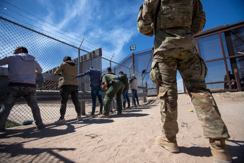 A Texas National Guardsman observes as Border Patrol agents pat down migrants who have surrendered themselves for processing, May 10, 2023. (Photo by Corrie Boudreaux for Source NM) A Texas National Guardsman observes as Border Patrol agents pat down migrants who have surrendered themselves for processing, May 10, 2023. (Photo by Corrie Boudreaux for Source NM)