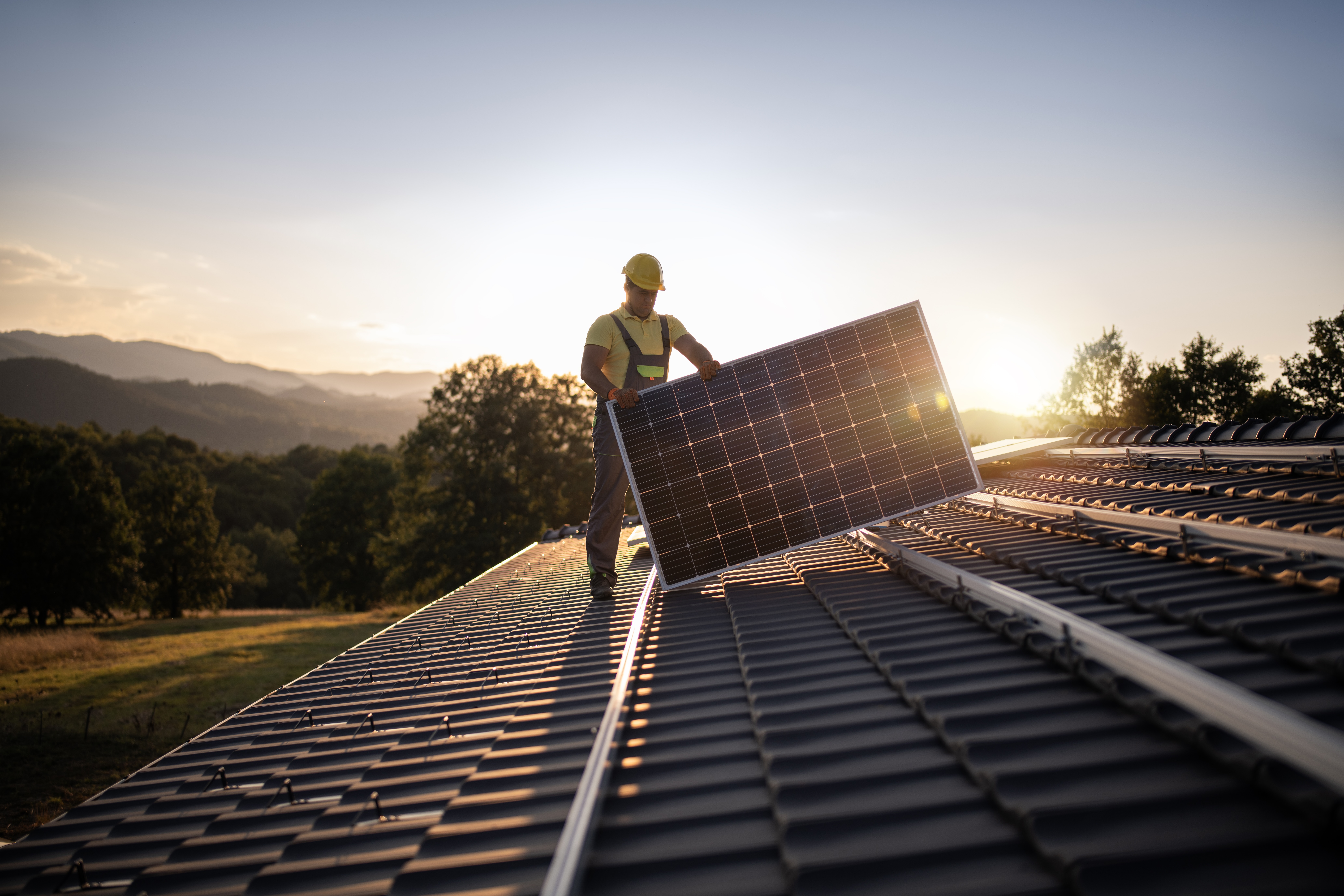 A worker installs a solar panel on a roof. (Getty Images)