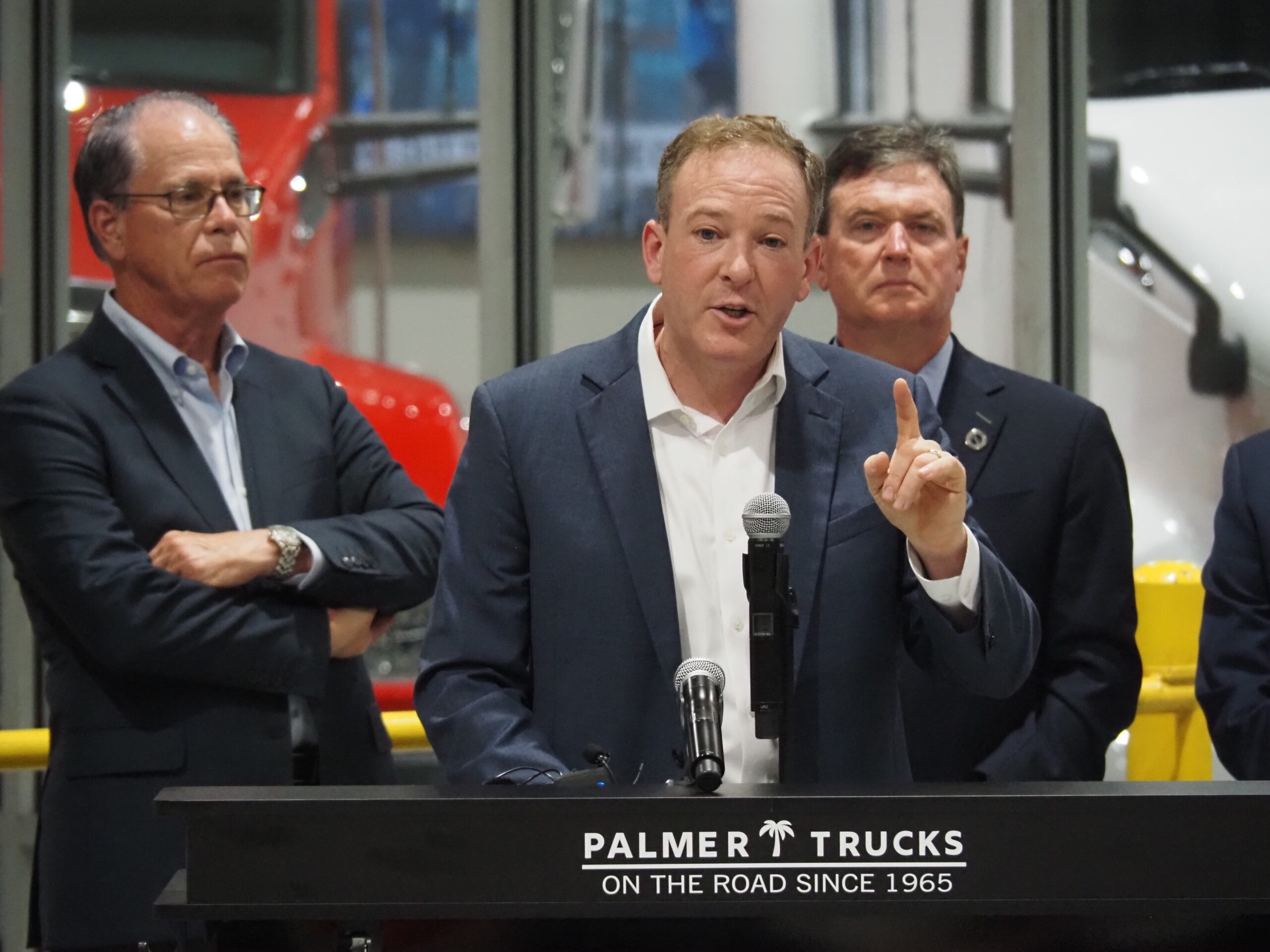EPA Administrator Lee Zeldin, center, announces his agency's plans for deregulation from an Indianapolis trucking facility on Tuesday, July 29, 2025. At left is Indiana Gov. Mike Braun and at right is Indiana Attorney General Todd Rokita.  (Photo by Leslie Bonilla Muñiz/Indiana Capital Chronicle)