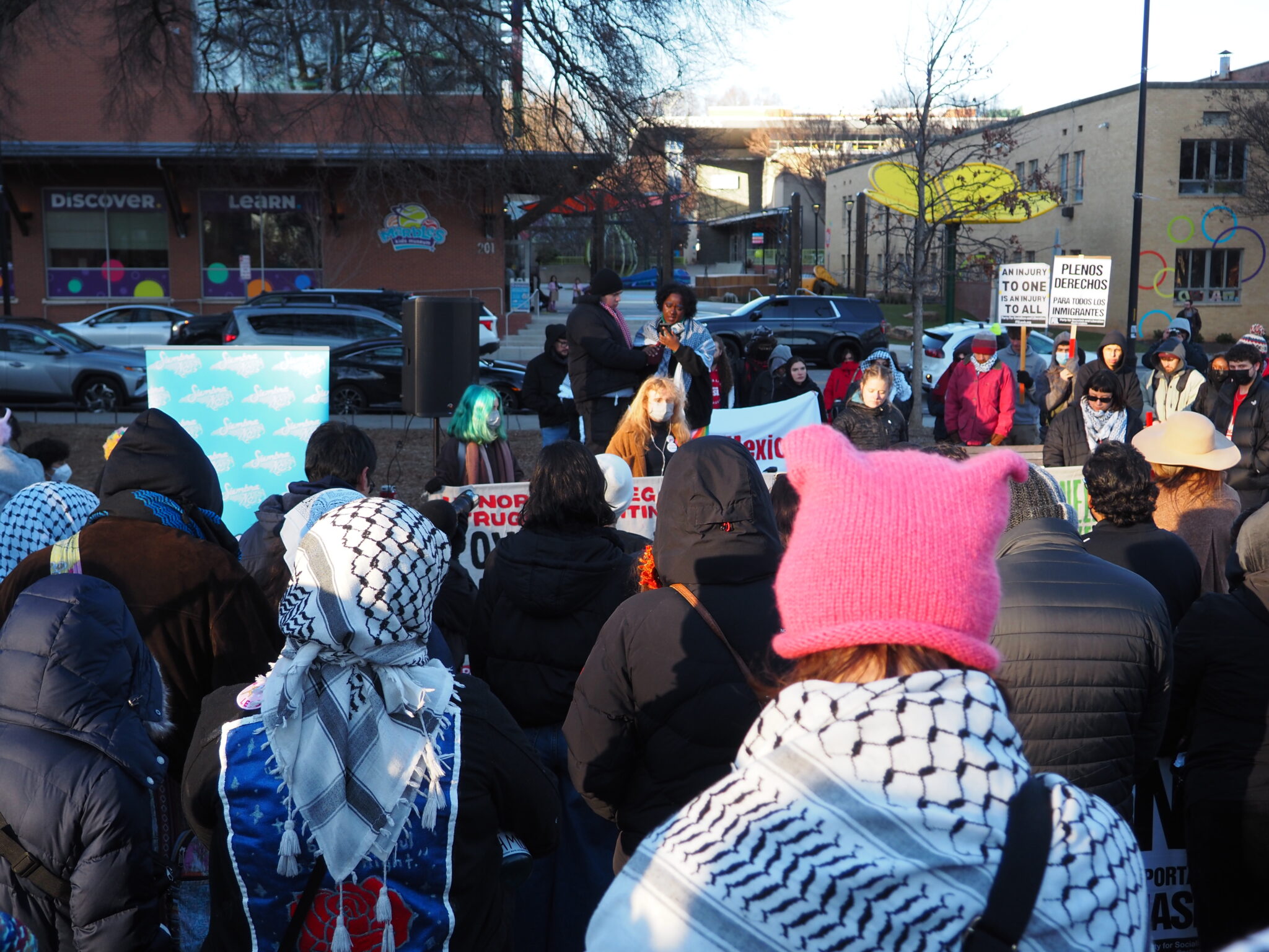 Hundreds protest Trump’s return to office in Raleigh as new resistance takes shape A woman in a pink hat with cat ears and a keffiyeh views speeches at a protest in Raleigh.