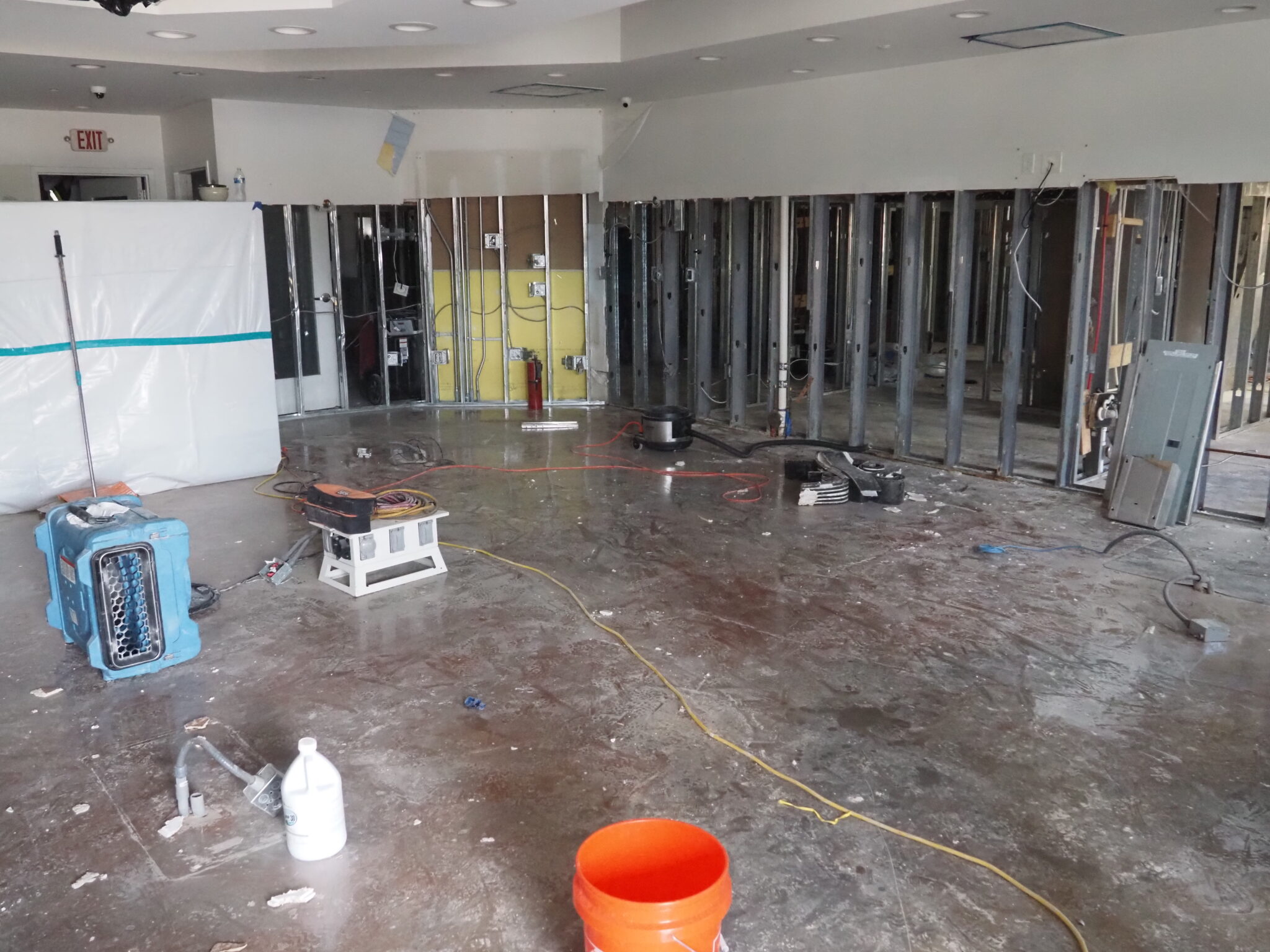 After Chantal flooding, Governor Stein surveys damage in Chapel Hill, urges federal relief A stripped building interior, with wall and floor coverings removed and a generator connected to machinery to dry the area.