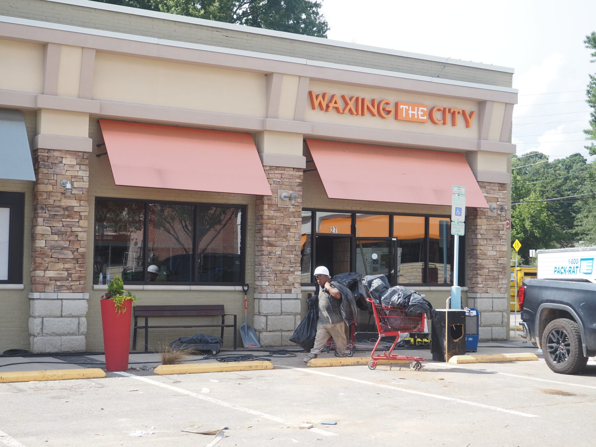 After Chantal flooding, Governor Stein surveys damage in Chapel Hill, urges federal relief A worker drags bags of debris out of Waxing The City. The parking lot beyonds its doors is littered with debris.