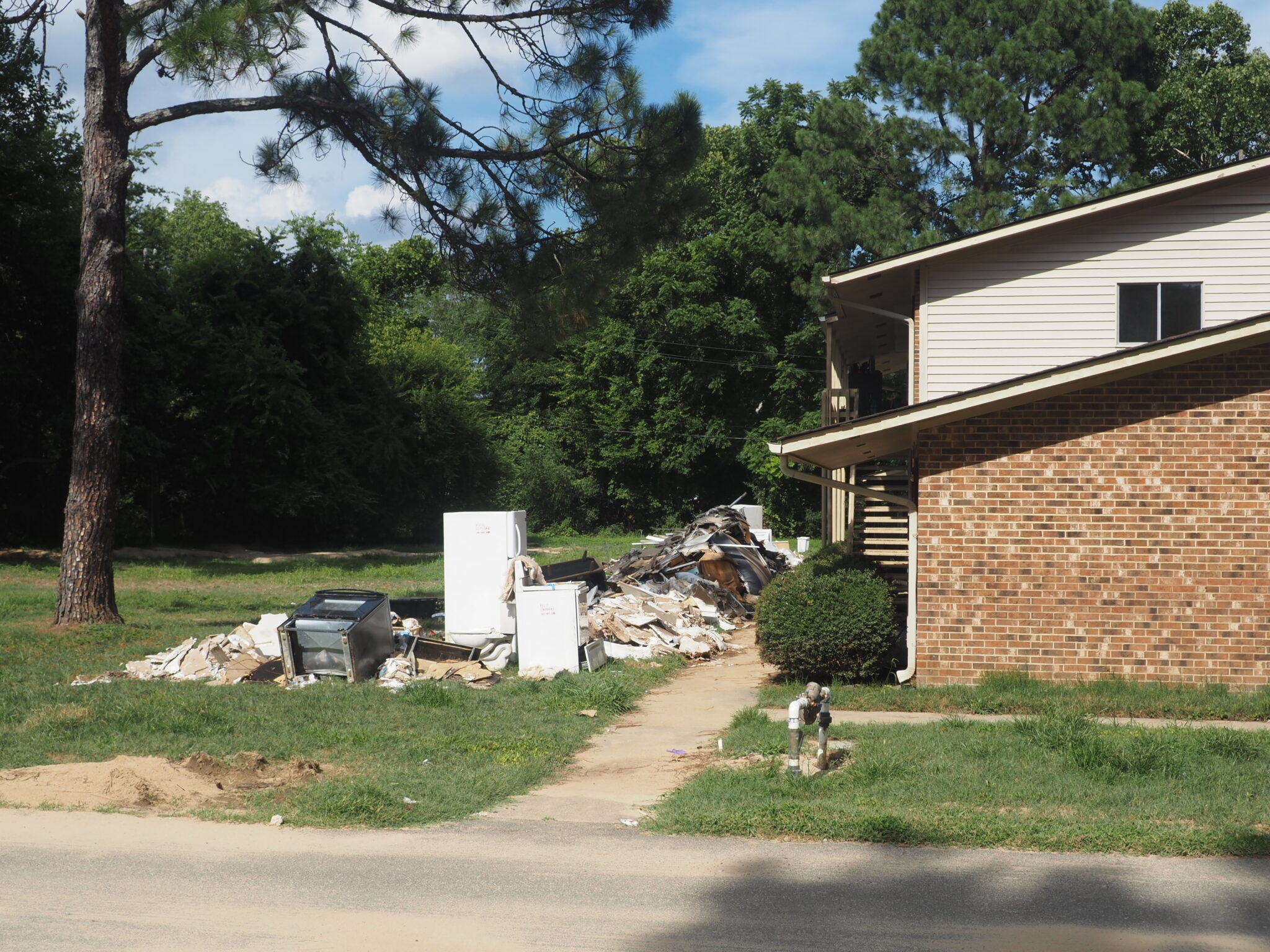 After Chantal flooding, Governor Stein surveys damage in Chapel Hill, urges federal relief A home with huge piles of debris in its yard, including large appliances such as an oven and a refigerator.