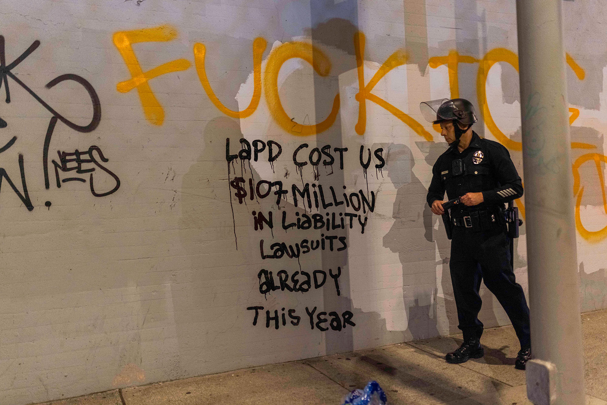 What it’s like to be in downtown LA as protests continue: ‘We’ve never seen it like this’ A law enforcement officer looks at graffiti on a concrete wall that says "LAPD Costs Us $107 million in liability lawsuits already this year."