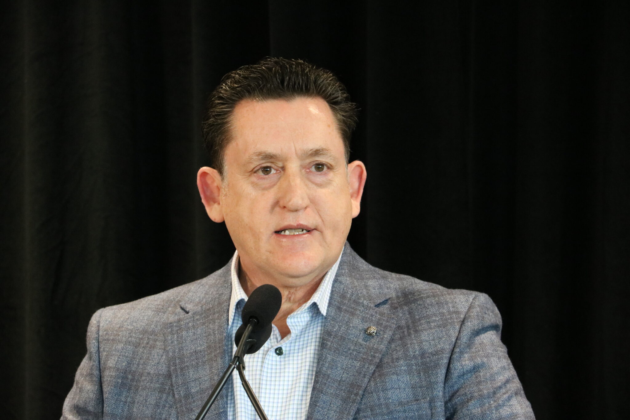 Bellar stands in front of a microphone.