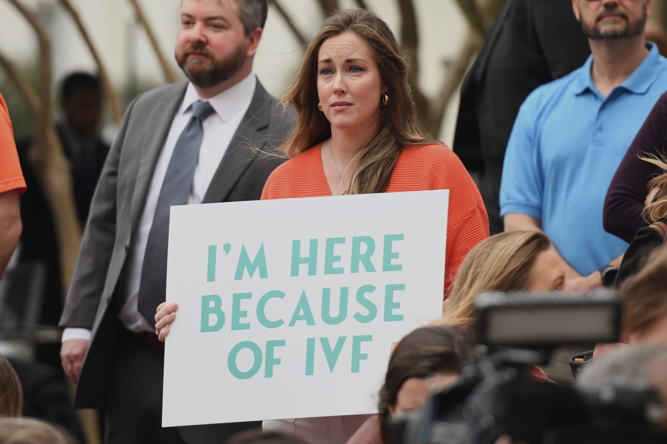 Bills aimed at protecting IVF advance in Alabama Legislature A woman holding a sign saying "I'm Here Because of IVF"
