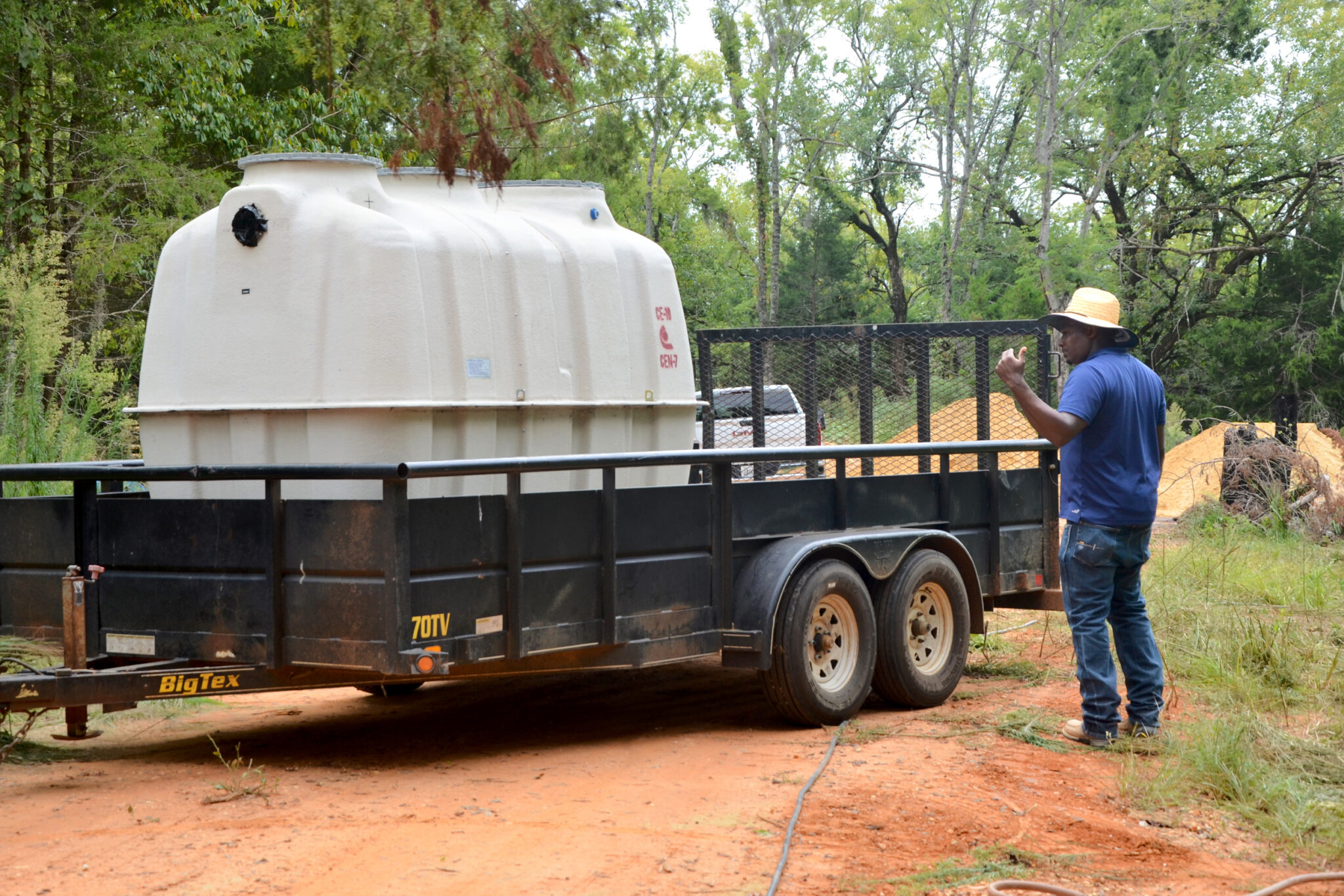 Alabama slowly bringing sanitation equity to rural Black communities after settlement A man standing next to a flatbed truck with a large plastic tank on it