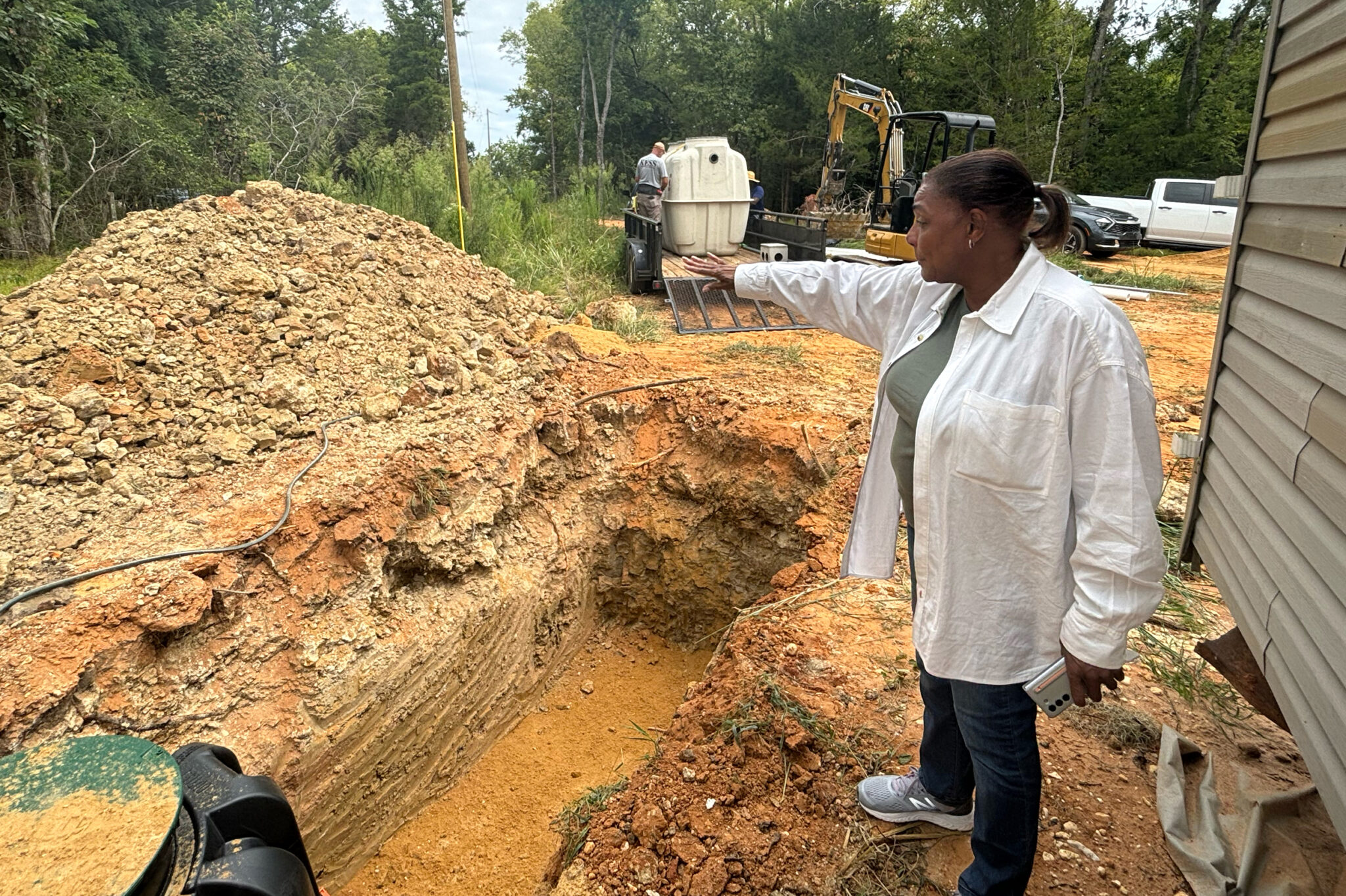 Alabama slowly bringing sanitation equity to rural Black communities after settlement A woman gesturing over a large hole in the ground