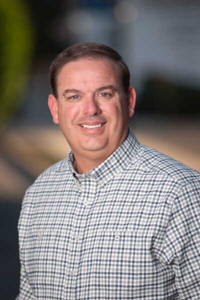 Matt Woods, Ryan Cagle square off in Senate District 5 election Man looks into a camera against blurred background for photo