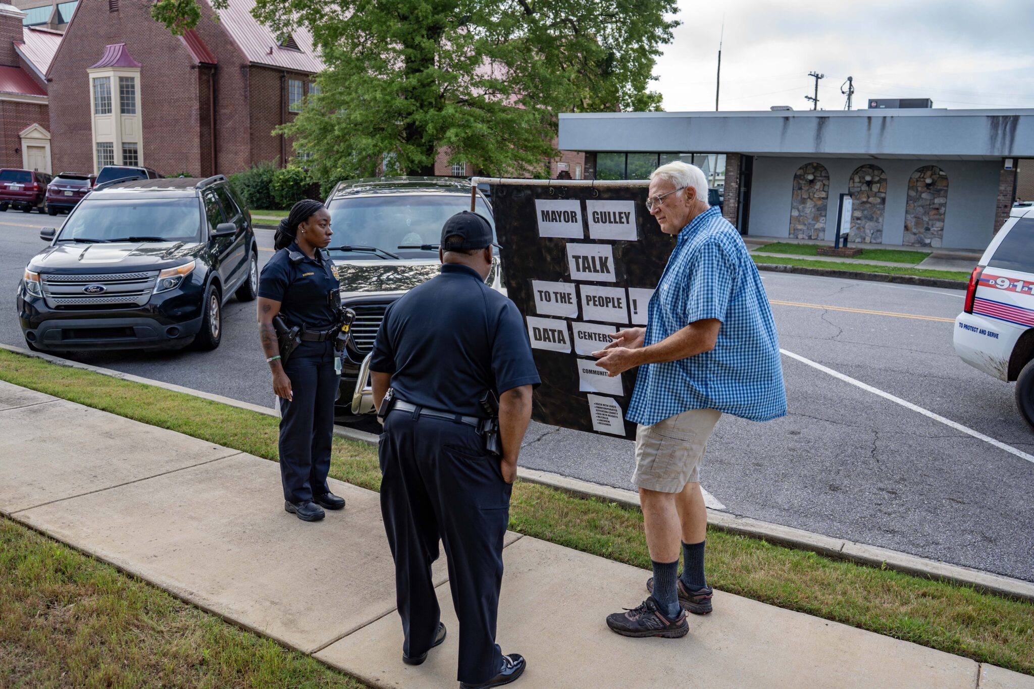 Proposed Bessemer data center could threaten endangered fish species A man with a large sign speaking to police officers