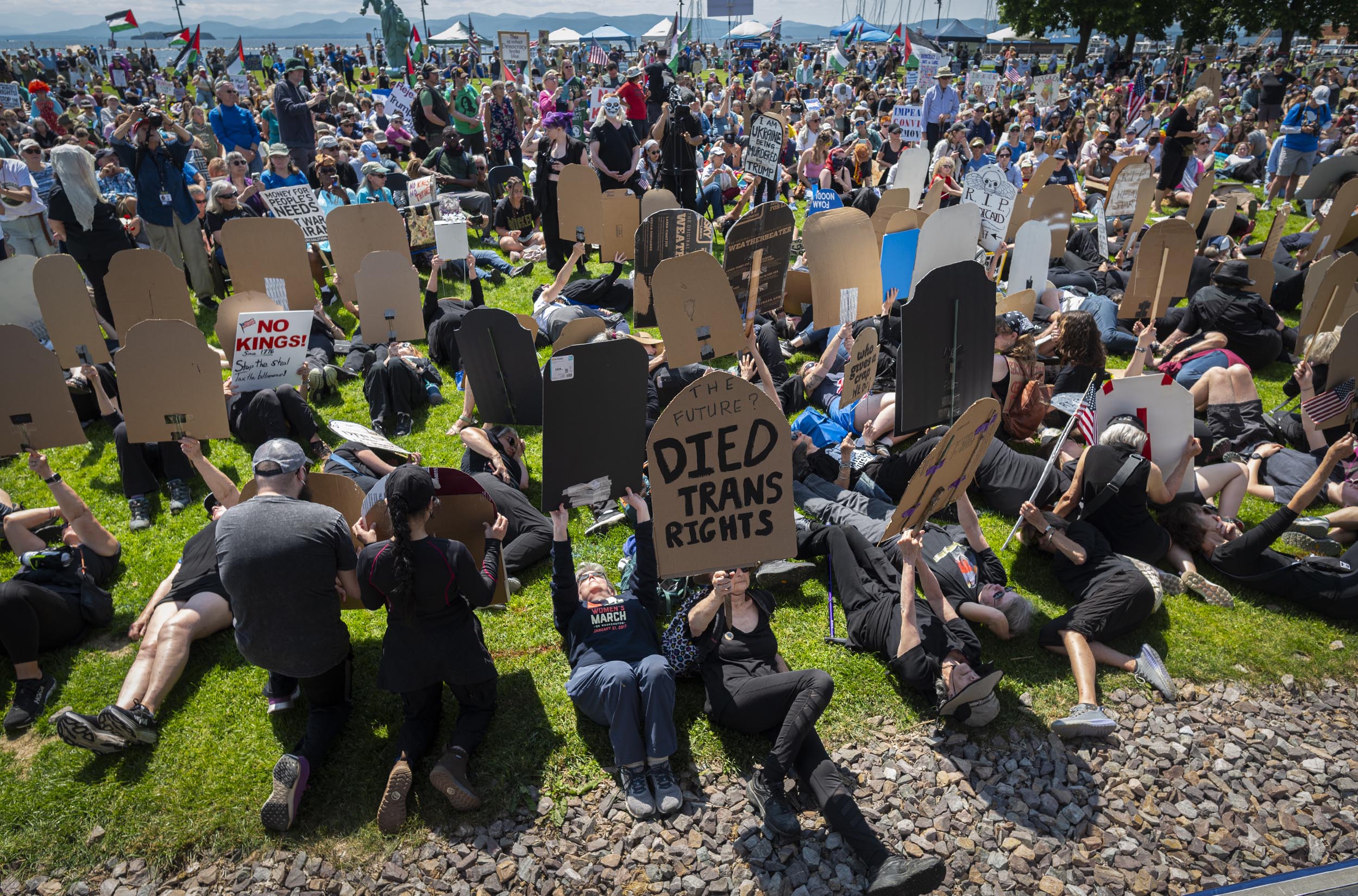 ‘No Kings Day’ draws more than 16,000 to Burlington to protest Trump and authoritarianism A large crowd of protesters lies on the grass holding signs shaped like gravestones, including one reading “Died Trans Rights,” during a demonstration.