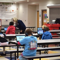 Students sit in a lunchroom in Arkansas on laptops