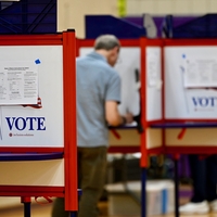 A man writes on a ballot in a voting booth in Maine