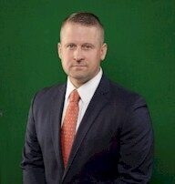 U.S. District Judge Matthew J. Kacsmaryk stands for a portrait against a green backdrop.