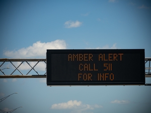 A digital sign above a busy highway alerts drivers to a current Amber Alert.