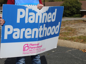 A volunteer clinic escort holds a sign outside a Planned Parenthood clinic in Columbia, South Carolina, on March 28, 2025. (Photo by Skylar Laird/SC Daily Gazette)