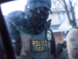 A masked U.S. Immigration and Customs Enforcement agent knocks on a car window in Minnesota on Jan. 12. (Photo by Nicole Neri/Minnesota Reformer)