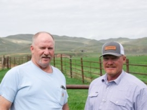 Tim Teichert and Jason Thornock, third-generation Cokeville ranchers, stand in Teichert’s backyard, where Thornock’s property and Rocky Mountain Power transmission lines are seen in the distance. (Jake Bolster/Inside Climate News)