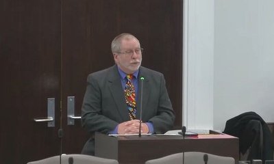 Timoth Hinds speaks into a microphone at a meeting