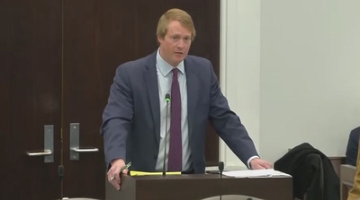 Weldon jones speaks into a microphone at a legislative meeting