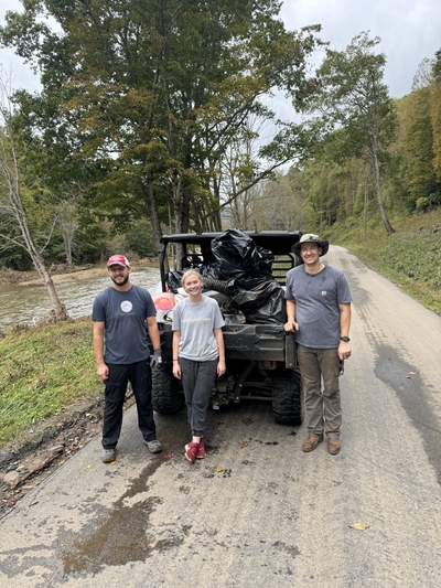 Three people stand in front of a four-wheeler filled with supplies in western North Carolina.