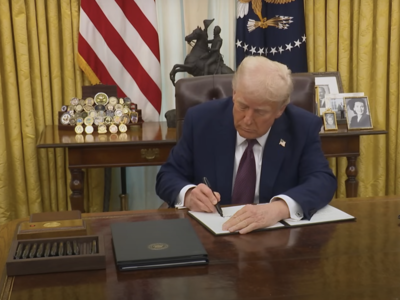President Donald Trump signs a memorandum in the Oval Office.