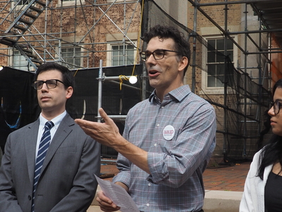 Michael Palm, wearing an AAUP button, gestures with his hand.
