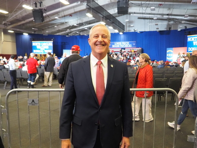 A man stands smiling in a suit at an event venue.