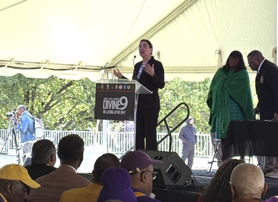Anita Earls speaks on a stage at a podium labeled Divine 9 Legislative Day.