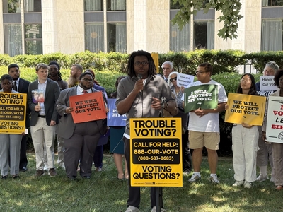 Jaden Foy speaks at a podium that reads, Trouble voting? Call for Help: 888-Our-Vote.