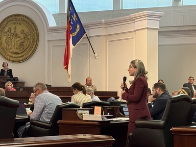 Sen. Sophia Chitlik stands and speaks into a microphone.