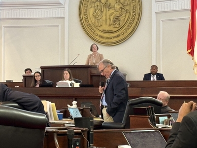 Bill Rabon looks down at his desk while speaking into a microphone.