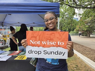 Krista Savage-White from Gates County holds a sign supporting Sunday voting on Aug. 20, 2026. (Photo: Clayton Henkel/NC Newsline)