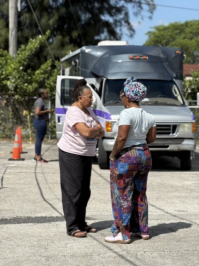 Jamarah Amani, executive director of the Southern Birth Justice Network, right, chats with midwife Sheila Simms Watson in front of the group’s RV mobile midwifery clinic in Miami at the Freedom Lab on March 21. (Photo by Nada Hassanein/Stateline)