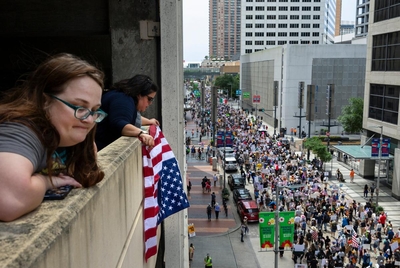 Guadalupe Lemon holds an upside down American flag as protestors march up Walker Street during a No Kings protest at City Hall, Saturday, June 14, 2025, in Houston.