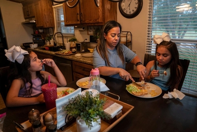 Clarissa Méndez, 44, and her daughters Catiana Ester Méndez, 7, left, and Catalaya Avaneh Méndez, 8, have diner at their home in Hebbronville, Texas on July 30, 2025. Méndez makes a daily one-hour commute to Laredo to work as a nurse. Currently she has her father or another person pick up her daughters from the daycare and take care of them for about an hour until she comes back from work. After picking up her daughters she cooks for them and spends some time with them before she starts working from hom