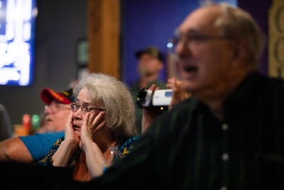A woman reacts to "Before" and "After" photos of land purchased for solar projects, at a community meeting at Penelope's Coffee in Mt. Vernon, on April 8, 2023.