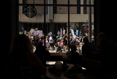 People watch the No Kings protest from a Starbucks on Saturday, June 14, 2025, in Dallas, Texas. The No Kings Day of Defiance was projected to be the largest single-day mobilization since Trump returned to office.