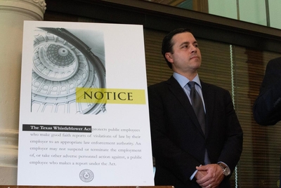 Whistleblower and former employee of the office of the Texas Attorney General Ryan Vassar stands next to a poster describing the whistleblower act on the agency's website, at a press conference at the Capitol in Austin on Sept. 25, 2023.