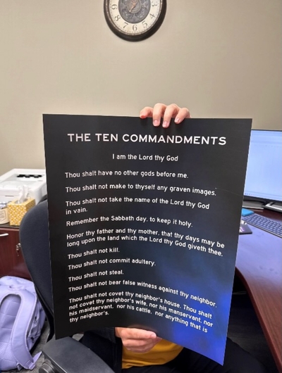 Person holding a Ten Commandments poster with white text and a black background