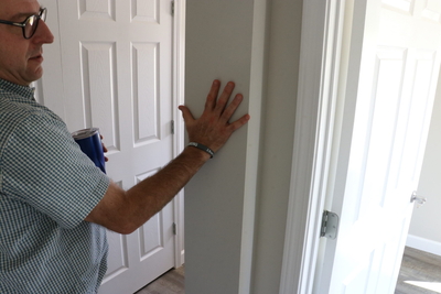 Tom Manning-Beavin puts his hand on the wall to signify where the "boxes" of the home come together.