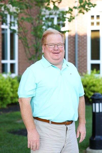 Dennis Harper poses in a teal shirt.