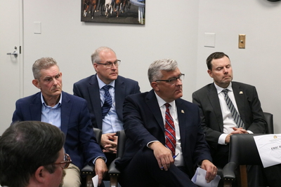 Men sit in chairs at the press conference.