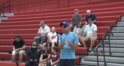 Gary stands in front of a microphone wearing a blue shirt.