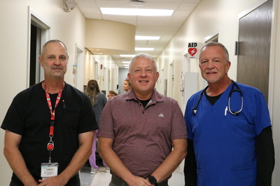 Three doctors pose in a hallway.