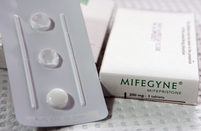 A blister pack with one of three pill remaining and a Mifegyne pill box behind it.