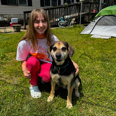 A girl posing with a dog in a backyard