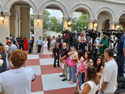 A small group of people in front of a line of television cameras